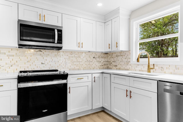 kitchen featuring white cabinets, light countertops, appliances with stainless steel finishes, and a sink