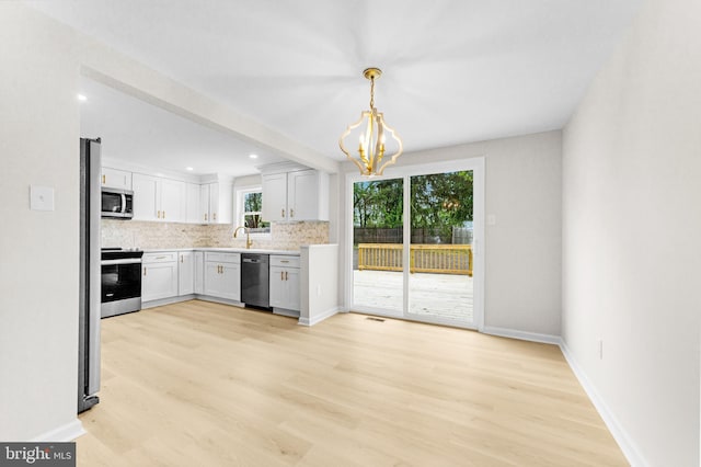 kitchen featuring light wood-style flooring, tasteful backsplash, light countertops, and appliances with stainless steel finishes