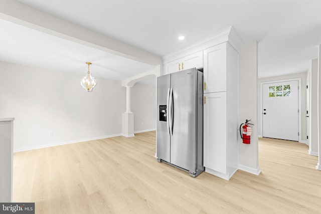kitchen with light wood-style flooring, stainless steel fridge, a notable chandelier, white cabinets, and baseboards