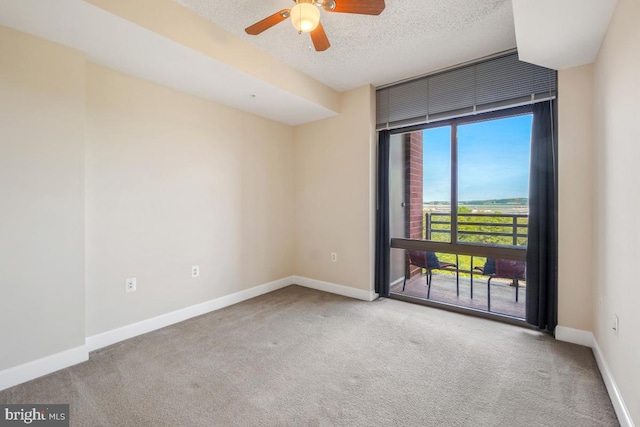 carpeted empty room featuring ceiling fan, baseboards, and a textured ceiling
