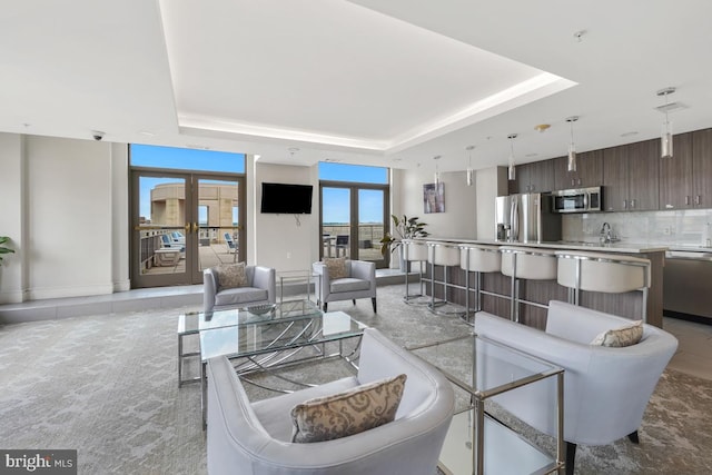 living room with a raised ceiling and french doors