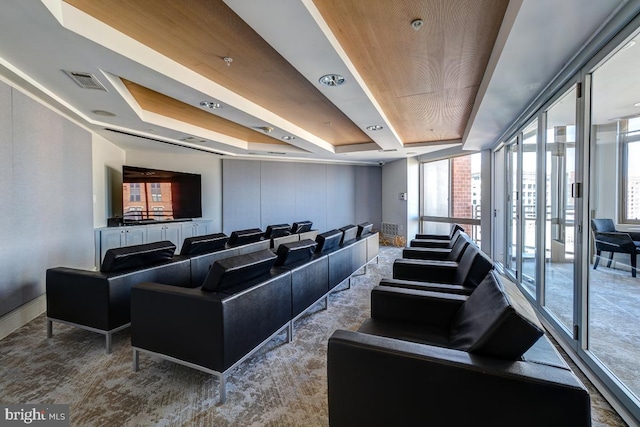 home theater room featuring baseboards, a tray ceiling, and visible vents