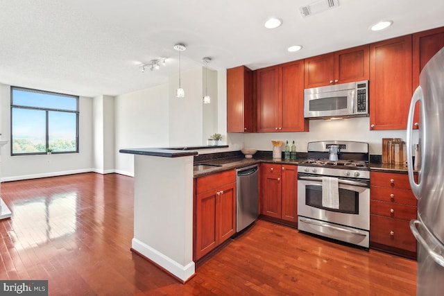kitchen with stainless steel appliances, a peninsula, dark wood-style floors, baseboards, and visible vents