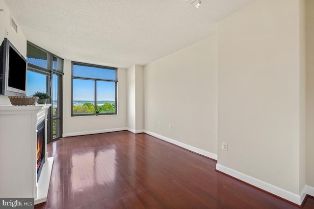 unfurnished living room featuring hardwood / wood-style floors, a textured ceiling, baseboards, and visible vents