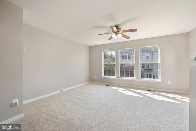 carpeted empty room with baseboards, a ceiling fan, and visible vents