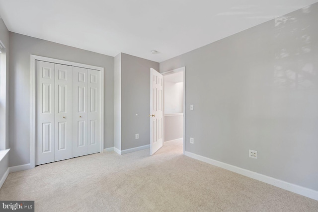 unfurnished bedroom featuring baseboards, carpet, and a closet