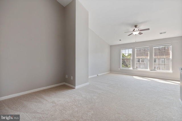 carpeted empty room with baseboards, ceiling fan, vaulted ceiling, and visible vents