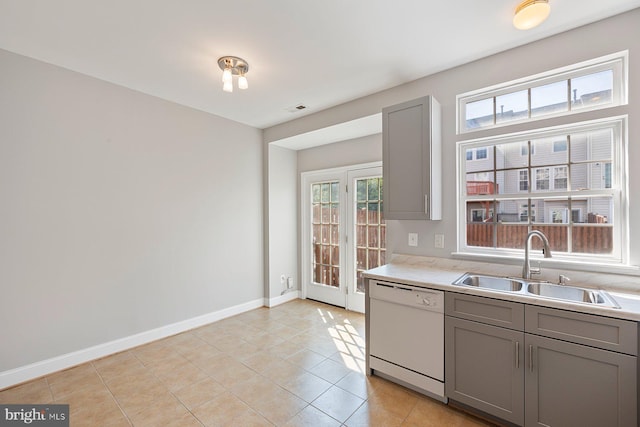 kitchen with visible vents, white dishwasher, light countertops, gray cabinets, and a sink