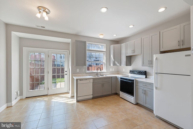 kitchen with a sink, white appliances, light countertops, gray cabinets, and light tile patterned floors
