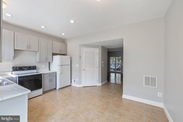 kitchen featuring electric range, light countertops, freestanding refrigerator, gray cabinetry, and visible vents