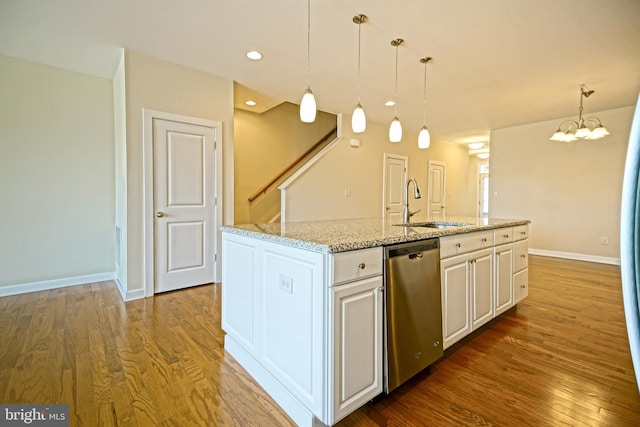 kitchen featuring light stone counters, a sink, wood finished floors, stainless steel dishwasher, and a center island with sink