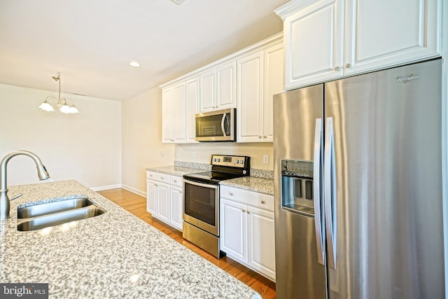kitchen featuring a sink, white cabinets, appliances with stainless steel finishes, and a chandelier