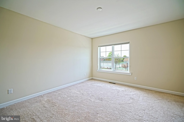 carpeted spare room with baseboards and visible vents