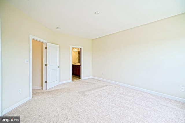 unfurnished bedroom with baseboards, light carpet, and ensuite bath
