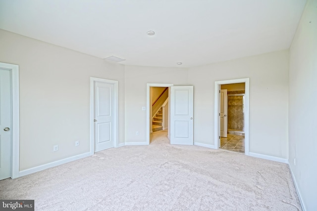 unfurnished bedroom with baseboards, connected bathroom, and carpet