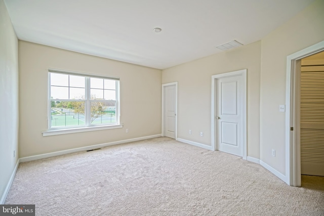 unfurnished bedroom with carpet floors, baseboards, and visible vents