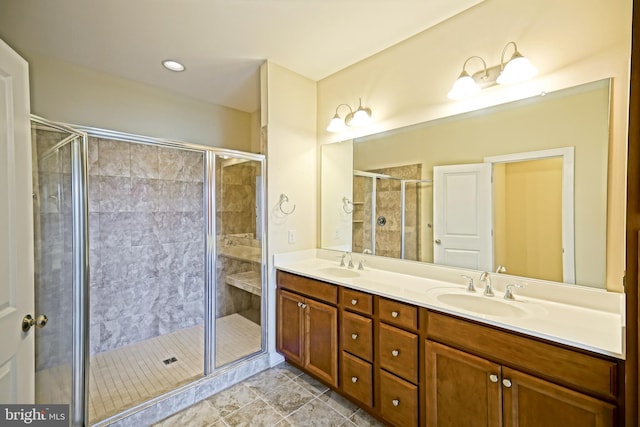 bathroom featuring double vanity, tile patterned floors, a shower stall, and a sink