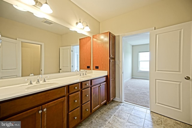 bathroom featuring visible vents, a sink, baseboards, and double vanity