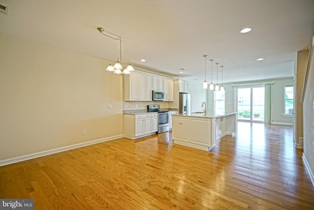 kitchen featuring a notable chandelier, baseboards, appliances with stainless steel finishes, and a sink