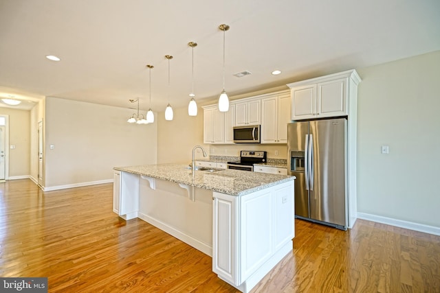 kitchen featuring baseboards, white cabinetry, a sink, light wood finished floors, and appliances with stainless steel finishes