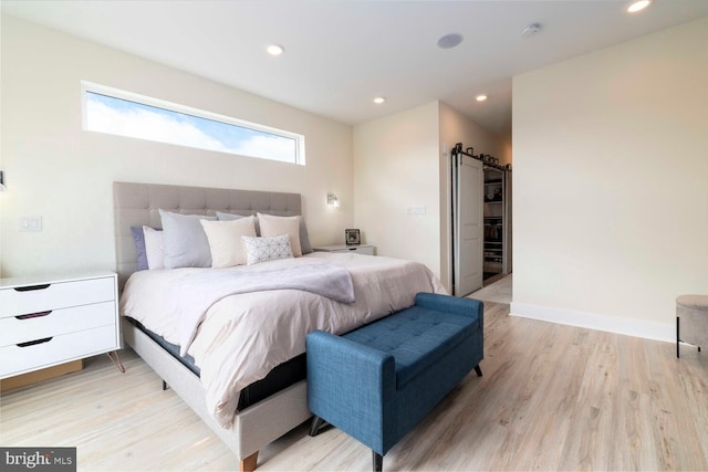 bedroom featuring a barn door, light wood-style floors, and recessed lighting