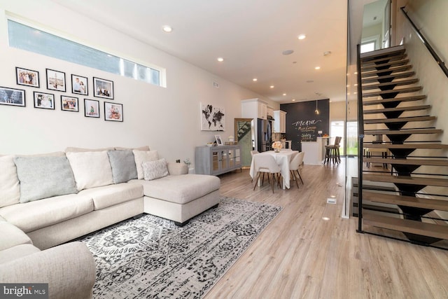 living area featuring recessed lighting, light wood finished floors, and stairs