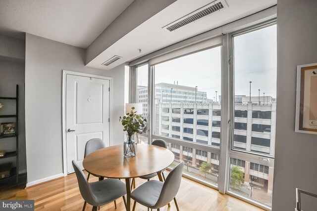 dining room featuring light wood finished floors, baseboards, and a city view