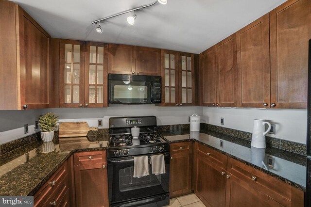 kitchen with black appliances, glass insert cabinets, dark stone countertops, light tile patterned flooring, and rail lighting