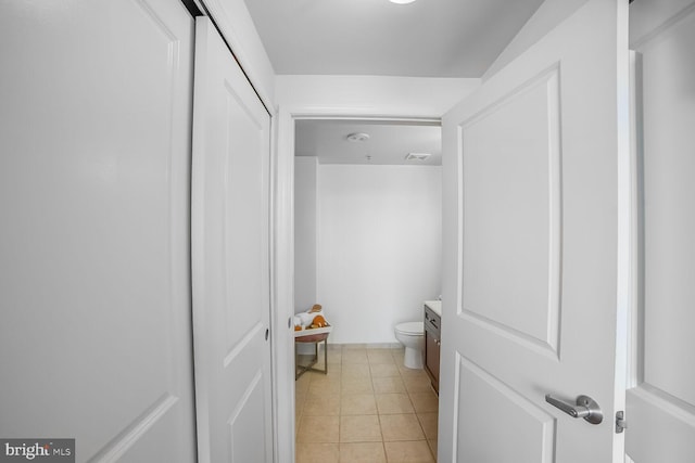 half bath featuring toilet, vanity, and tile patterned flooring