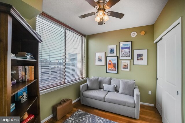sitting room featuring wood finished floors, baseboards, and ceiling fan