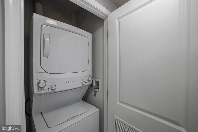 clothes washing area with stacked washing machine and dryer
