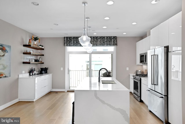 kitchen with light wood-type flooring, appliances with stainless steel finishes, a sink, and white cabinetry