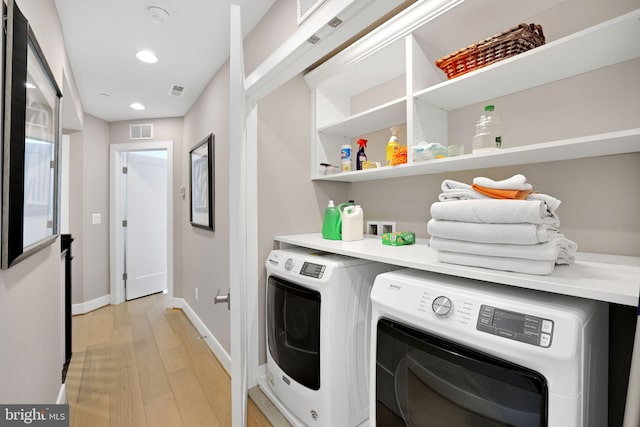 laundry room with laundry area, light wood-style floors, visible vents, washer and dryer, and baseboards