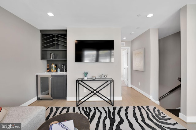 living area featuring light wood-style flooring, a dry bar, beverage cooler, and recessed lighting