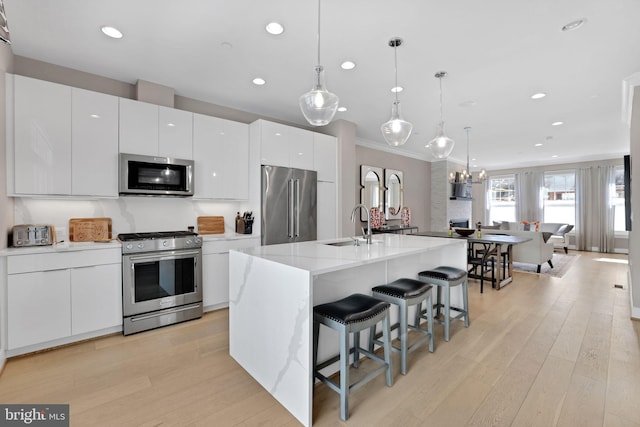 kitchen with a kitchen breakfast bar, crown molding, light wood-style floors, appliances with stainless steel finishes, and a sink