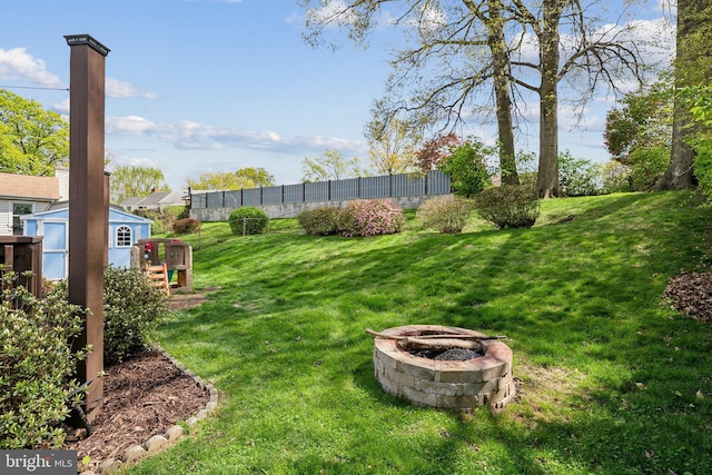 view of yard with a storage shed, an outbuilding, an outdoor fire pit, and fence