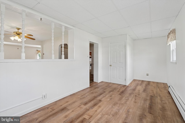 interior space with a drop ceiling, baseboards, baseboard heating, wood finished floors, and a ceiling fan