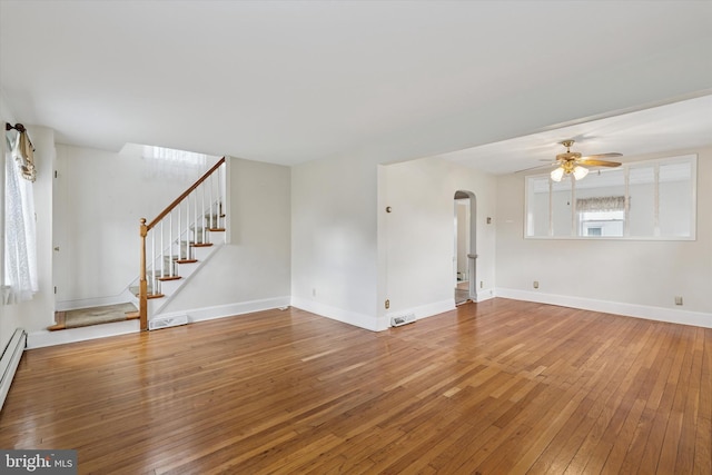 unfurnished living room featuring arched walkways, visible vents, stairway, ceiling fan, and hardwood / wood-style floors