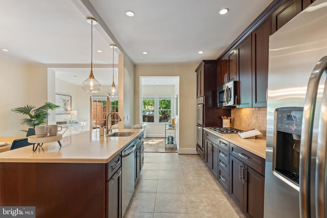 kitchen featuring appliances with stainless steel finishes, a sink, tasteful backsplash, light tile patterned flooring, and light countertops