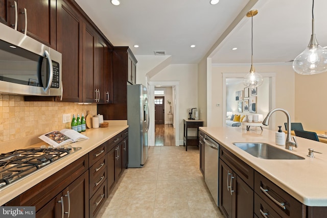 kitchen with appliances with stainless steel finishes, a sink, light countertops, light tile patterned floors, and dark brown cabinetry