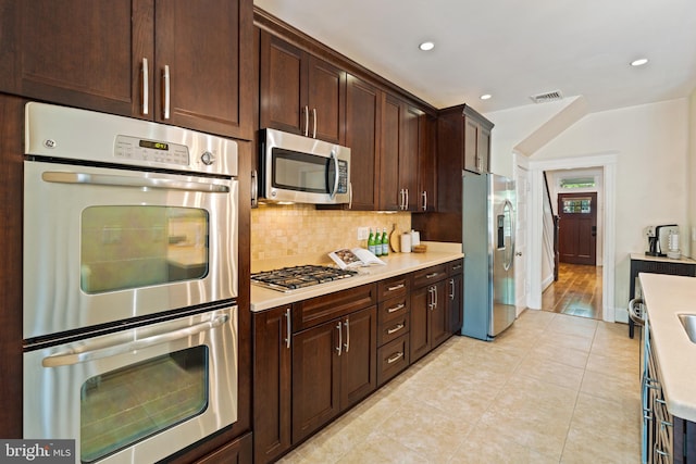 kitchen featuring stainless steel appliances, light countertops, decorative backsplash, light tile patterned floors, and recessed lighting