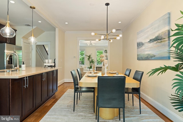 dining space featuring crown molding, wood finished floors, baseboards, recessed lighting, and a chandelier