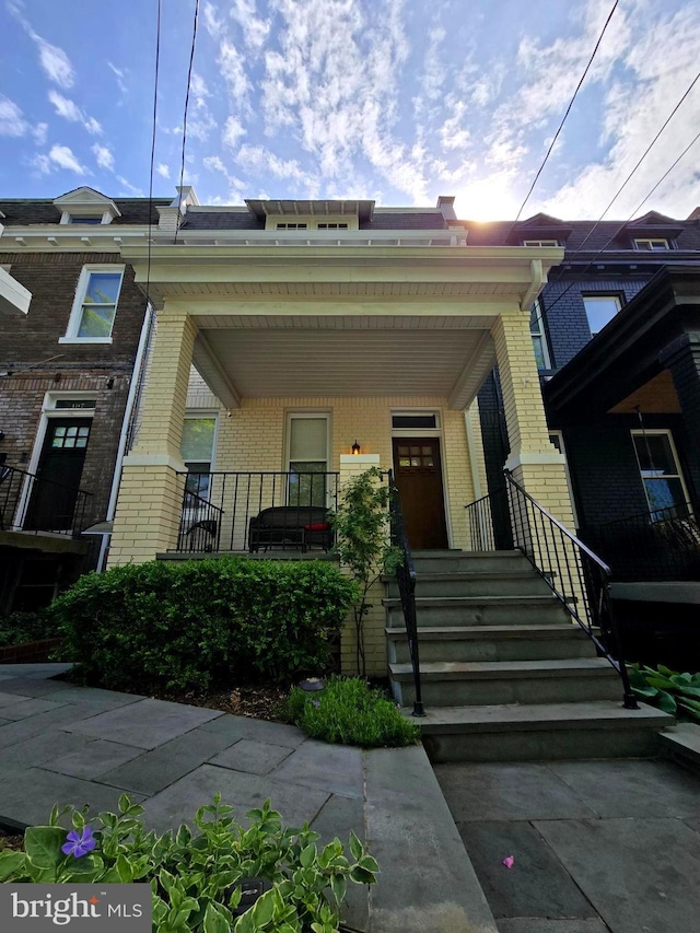 view of front of house featuring brick siding and a porch