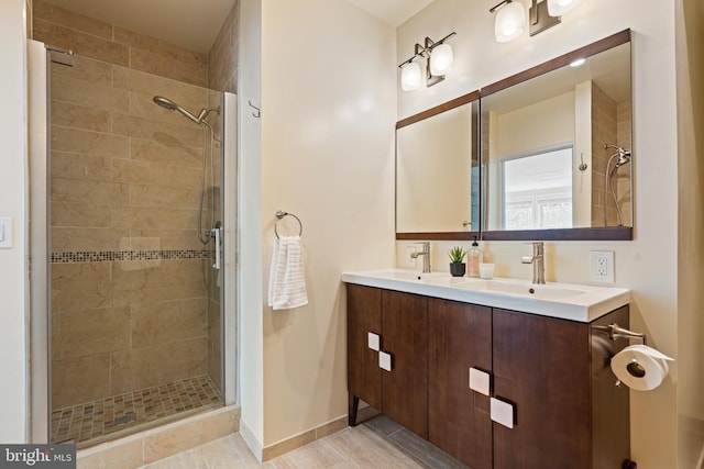 bathroom with a stall shower, double vanity, and baseboards