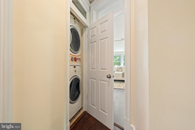 clothes washing area featuring stacked washing machine and dryer and dark wood-type flooring