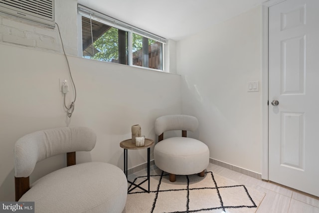 living area featuring baseboards and an AC wall unit