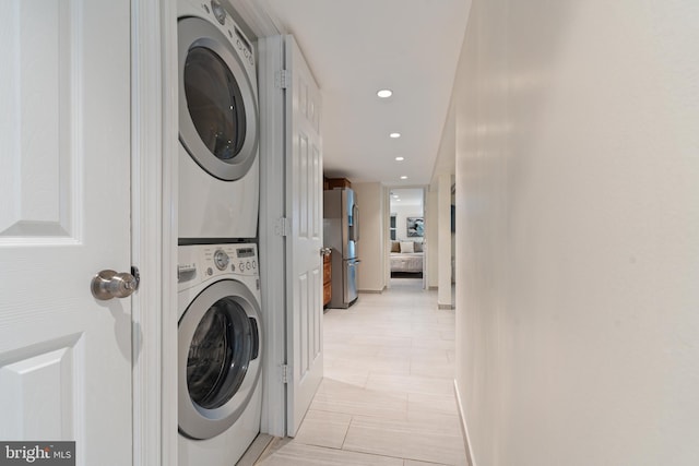 laundry area featuring stacked washing machine and dryer, recessed lighting, and baseboards