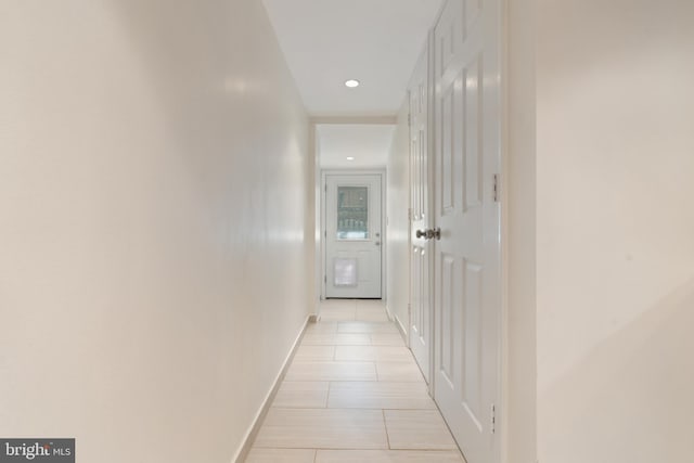 hall featuring baseboards, light tile patterned floors, and recessed lighting