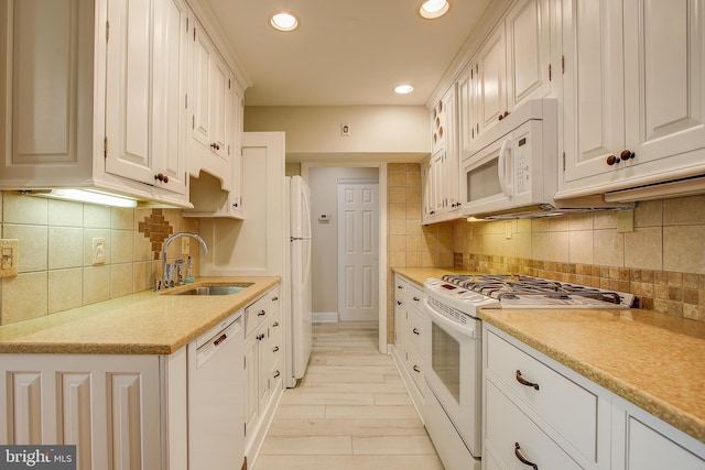 kitchen featuring a sink, white appliances, light countertops, recessed lighting, and backsplash