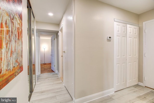 hall with light wood-style floors, baseboards, and recessed lighting